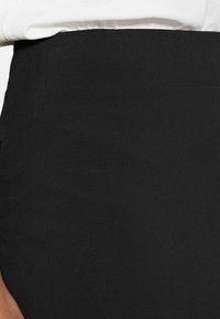 Jupe crayon noire avec une texture lisse, un design ajusté et des détails de coutures subtils, dotée d'une taille haute et sans quincaillerie visible.