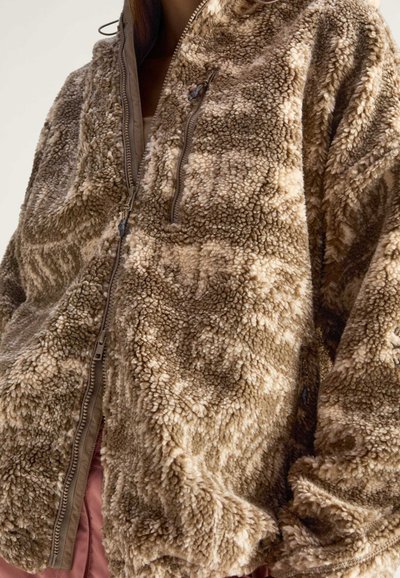 Bruine harige zip-up jas van zacht, gestructureerd materiaal met een capuchon en een lichte geometrische patroon. Bevat contrasterende rits en zakken.