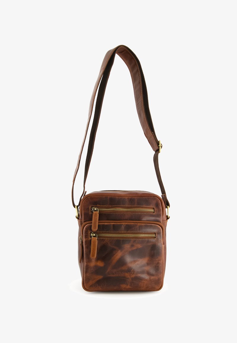 Brun læder crossbody taske med to frontlommer med lynlås, justerbar rem og en glat, tekstureret overflade. Kompakt rektangulært design.