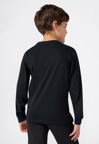 Camiseta de manga larga de algodón negro con un cuello redondo clásico, textura suave y un corte relajado. Sin logotipos ni patrones visibles.