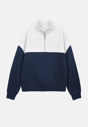 Poolsaagiga pusasärk, mille ülemine osa on valge ja alumine osa ning varrukad tumesinised, koos seiseva krae ja pikkade varrukatega.