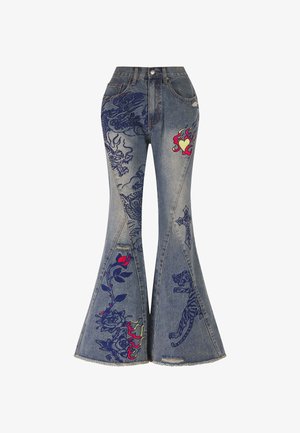 Jeans en denim bleu évasés avec des motifs brodés complexes, présentant un dragon, un tigre et des accents floraux en rouge et bleu marine. Ourlet effiloché.