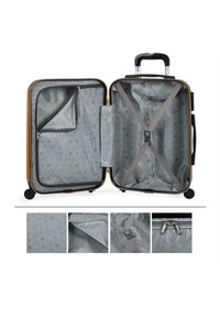 Maleta de concha dura con un exterior amarillo, interior gris que presenta un patrón geométrico, múltiples compartimentos y correas ajustables.