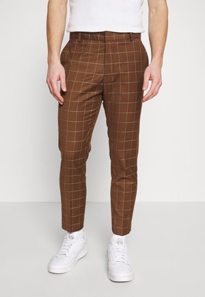 Bruine geruite broek met een slim fit, voorzien van een ruitjespatroon, zakken aan de zijkant en gecombineerd met witte sneakers.