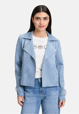 Helle blaue Kunstwildlederjacke mit spitzem Kragen und offener Vorderseite, ausgestattet mit langen Ärmeln und Knopfdetails an den Bündchen über einem weißen T-Shirt.