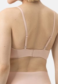 Light pink padded bra with adjustable straps and a clasp closure, featuring a smooth texture and minimalistic design.