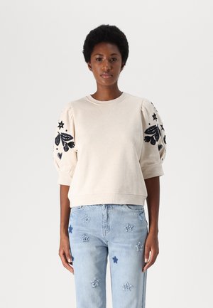 Light beige sweatshirt with puffed sleeves, featuring black floral and star embroidery on the arms. Cotton blend fabric, relaxed fit.