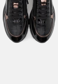 Svarta lacklädersneakers med krokodilstruktur, med bronsdetaljer och svarta snören. Rundad tå och vadderad krage.