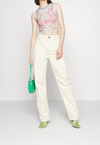 Klippt, ärmlös topp i pastellgrön med rosa blommönster, tillsammans med krämfärgade vida byxor. Tillbehör inkluderar en grön väska med krokodilsmönster och gröna klackar med remmar.