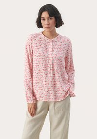 Ljusrosa långärmad blus med ett geometriskt bladmönster i mörkare nyanser av rosa, med rundad halsringning och knapprad.