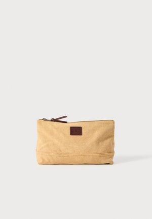 Pochette en toile beige avec fermeture éclair, accent en cuir marron et petite patch logo. Présente une forme rectangulaire et une texture durable.