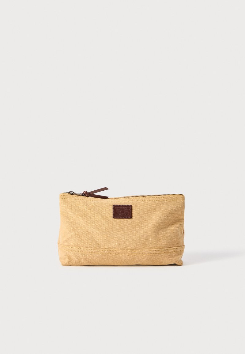 Pochette en toile beige avec fermeture éclair, accent en cuir marron et petite patch logo. Présente une forme rectangulaire et une texture durable.