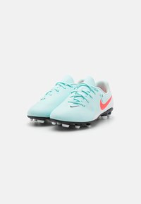 Light blue soccer cleats with a smooth texture, white accents, and a pink Nike swoosh. Features black studs on the sole for traction.