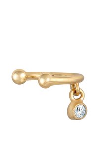 Anillo de color dorado que presenta dos elementos esféricos y un charm colgante con una piedra preciosa transparente. El diseño es elegante y minimalista.