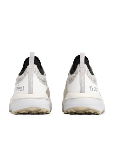 Baskets de sport blanches et grises avec un tissu texturé, des accents noirs et une marque distincte au talon. Présentent une semelle en caoutchouc robuste.