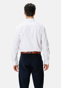 Hvid skjorte med lange ærmer og knap-ned krave, parret med marineblå bukser og et brunt læderbælte. Glat stof, skræddersyet pasform.