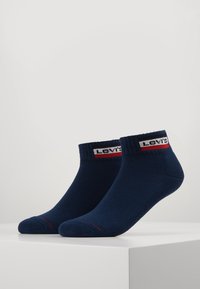 Tengerészkék bokaszobák bordázott felső résszel, piros és fehér Levi's logós sávval. Puha tapintás, varrás nélküli lábujjak és minimalista dizájn.