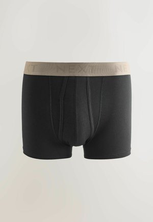 Svarta boxershorts med beige resårmidja med texten "NEXT." Försedda med en framficka och ett mjukt tyg.