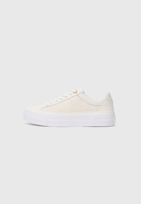 White sneaker with a textured fabric upper, smooth leather accents, flat white laces, and a thick white rubber sole. Gold-tone eyelet detail.