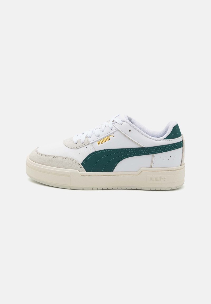 Baskets Puma blanches basses avec bande latérale vert foncé, bout beige, semelle beige et logo Puma doré sur le côté.