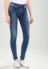Skinny jeans i mörkblå denim, med fem fickor, knapp- och dragkedjestängning samt en mjuk yta. Matchas med vita sneakers.