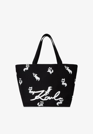 Mustmustrepp, millel on valged karikatuuridega rebased ja nimi "Karl" rasvases valges kirjas. Valmistatud vastupidavast kangast ja tugevate õlapaeltega.