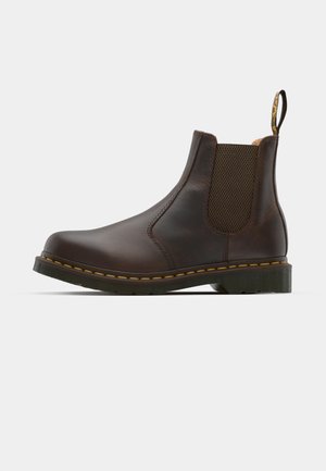 Brown leather Chelsea boot with elastic side panels, textured heel, and contrast yellow stitching. Features a pull tab for easy wear.
