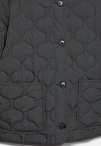 Ciemnoszara pikowana kurtka z przodu z czterema czarnymi guzikami, dwoma kwadratowymi kieszeniami i wzorem szwów w kształcie chmurki.