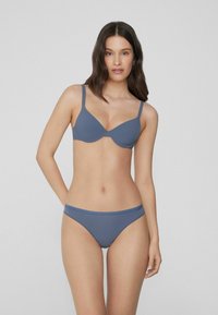 Ensemble de lingerie bleu comprenant un soutien-gorge et un bas bikini en tissu extensible et lisse. Le design inclut des bretelles réglables et des bords sans couture.