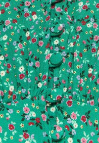 Grüner Blumenkleid-Stoff mit kleinen pinken, roten und lila Blumen. Verfügt über runde Stoffknöpfe an der Vorderseite und eine geraffte Textur.