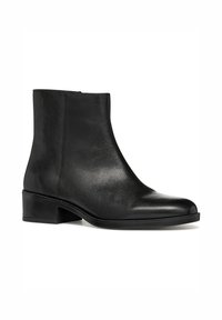 Bottine en cuir noir avec une texture lisse, bout arrondi, petit talon empilé et un subtil détail de couture le long de la semelle.