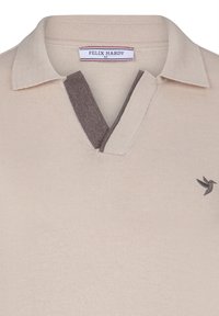 Béžové pletené polo tričko s tmavohnědým límcem. Na tričku je decentní logo ptáka v tmavohnědé barvě. Materiál má měkký, strukturovaný vzhled.