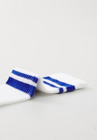 Calcetines blancos con rayas horizontales azules, textura acanalada y material suave. El diseño incluye dos rayas más gruesas y una más delgada.