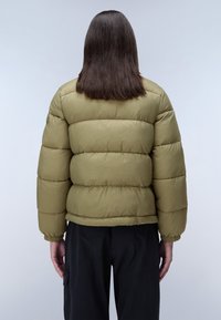 Olivgrön puffjacka med en kortad design, med kviltade sektioner och elastiska manschetter. Bakifrån syns en slät textur och rena linjer.