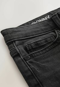 Čierne úzke džínsy vyrobené z denimu, so predným vreckom, šitými švami a detailom na gombíku. Pás má štítok "SKINNY".