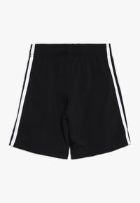 Bermudas negras con rayas laterales blancas, fabricadas en una tela suave. Cintura elástica para mayor comodidad. Diseño simple y deportivo con líneas limpias.