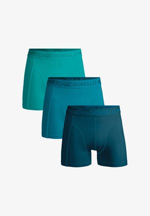 Tres pares de bóxers de hombre en tonos variados de verde azulado y azul oscuro, con una textura suave y cintura elástica con el logo "MUCHACHO".