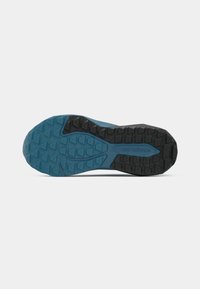 Gumeni dio plave i crne New Balance tenisice s teksturiranim trokutastim uzorkom na bijeloj pozadini.