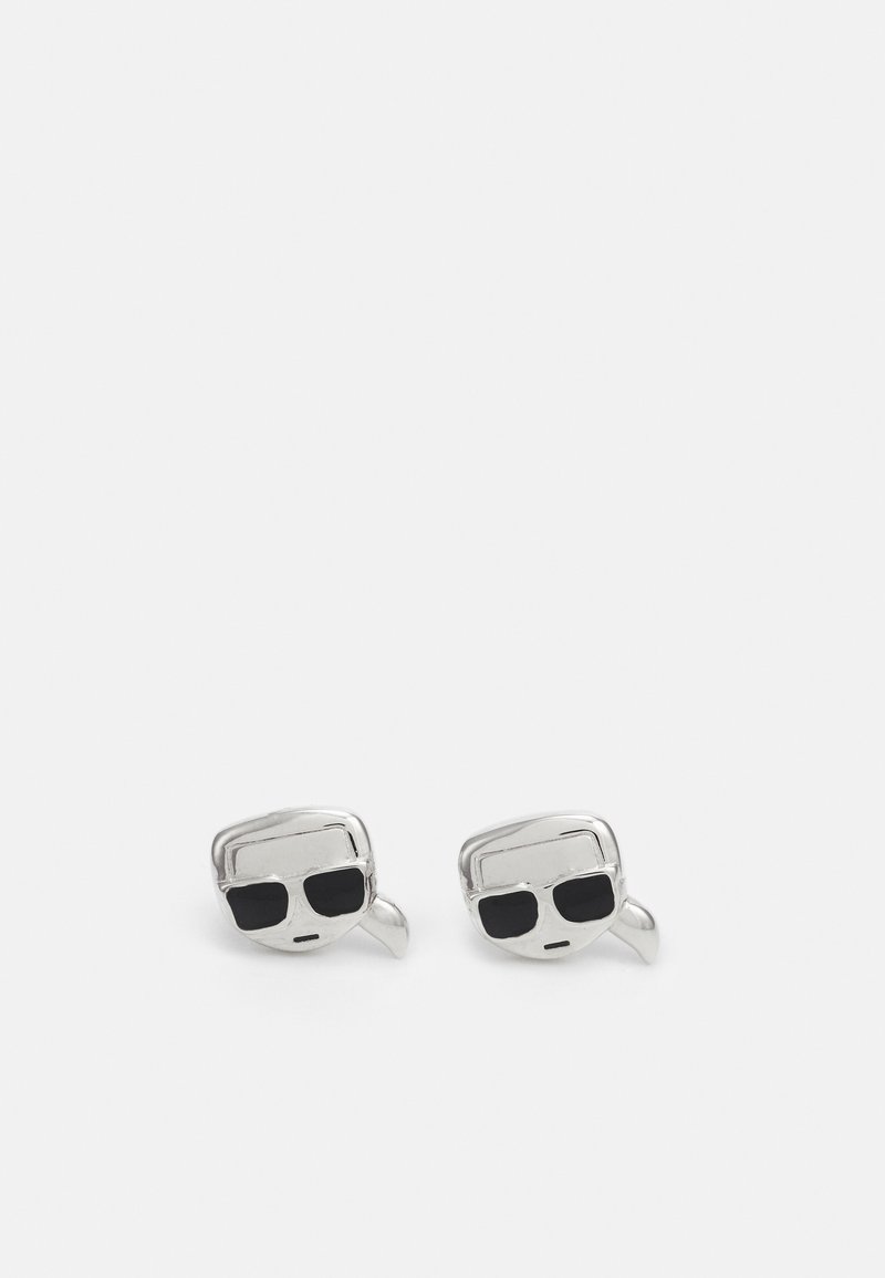 Paire de boutons de manchette en argent en forme de visages avec des lunettes de soleil noires et une bouche en ligne droite sur fond blanc.