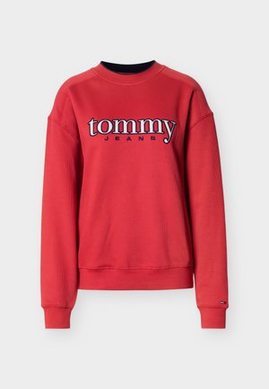Felpa rossa in cotone con trama a costine, collo rotondo e spalle scese. Presenta le scritte "tommy" e "JEANS" ricamate in colori a contrasto.