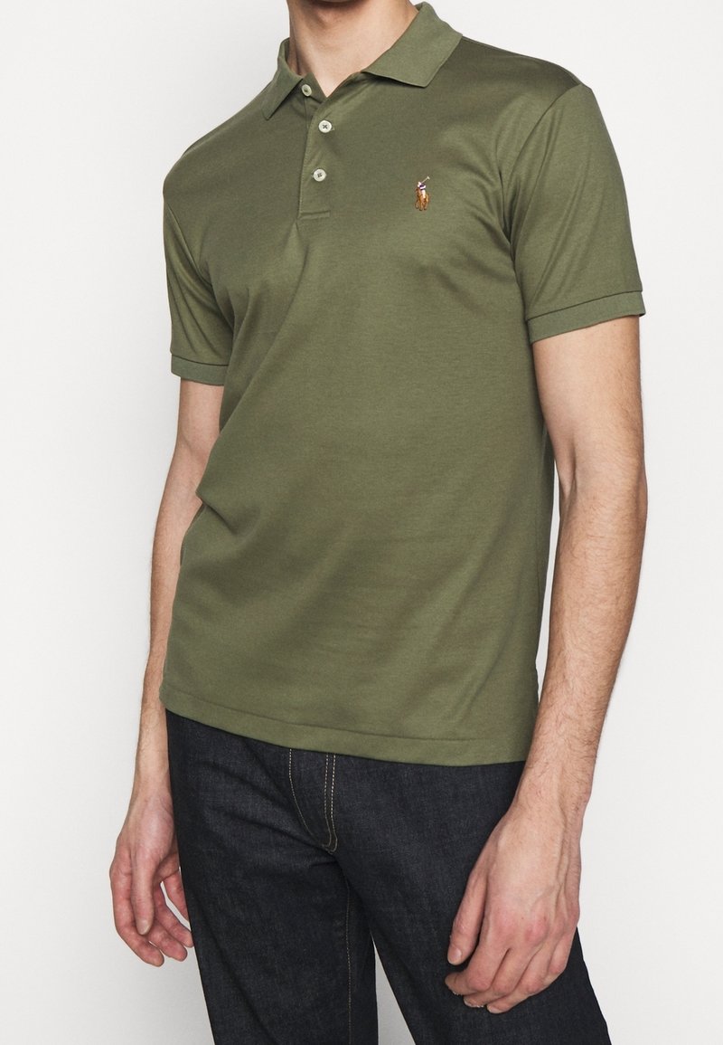 Olivgrön polo med kort ärm, tillverkad av bomull, med en tre-knapps knäppning och en liten broderad logotyp på vänster bröst.