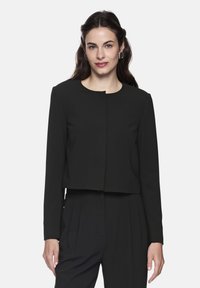 Black cropped jacket with long sleeves, round neckline, and front clasp detail. Made of smooth fabric with a structured shape.