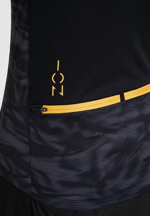 Schwarze und dunkelgraue Sportbekleidung mit einem gelben horizontalen Reißverschluss und einem kleinen gelben abstrakten Logo oberhalb des Reißverschlusses.