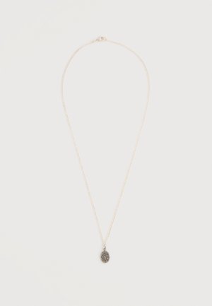 Collier délicat en chaîne d'argent avec un petit pendentif ovale foncé présentant des détails texturés, présenté sur un fond clair.