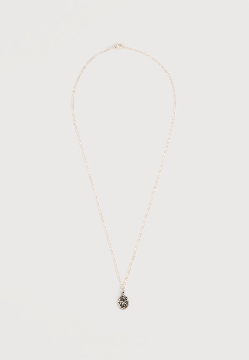 Colier delicat din lanț de argint cu un mic pandantiv oval închis la culoare, cu detalii texturate, expus pe un fundal deschis.