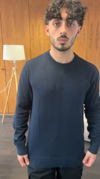 Mornarsko moder pleten pulover s okroglem izrezom in rebrastimi manšetami, ki se ponaša z gladko teksturo in ravnim robom.