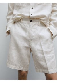 Beige linnen shorts met een relaxed fit, voorzien van een knoopsluiting, zijzakken en een licht gestructureerd oppervlak.