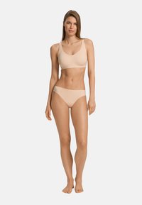 Set di reggiseno wireless beige e slip coordinato, realizzato in tessuto morbido. Il reggiseno presenta spalline larghe e un collo arrotondato.
