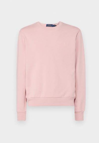 Lys rosa hettegenser laget av myk stoff, med lange ermer, rund hals, og en liten gull-logo på brystet. Jevn tekstur.