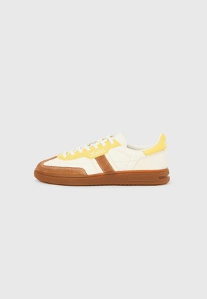 Low-top sneaker with cream, yellow, and brown suede panels, white laces, and rubber sole, featuring Polo and Ralph Lauren branding.
